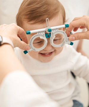 A blond kid smiling getting a pediatric eye health exam